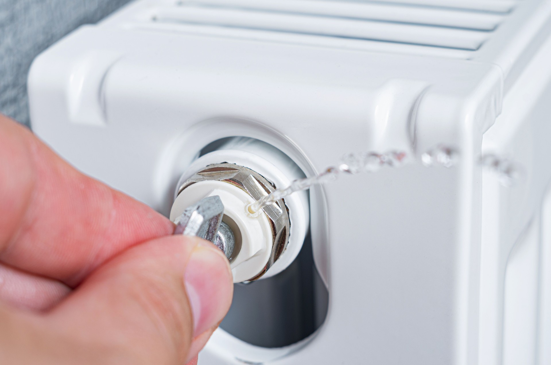 The bleed valve in the radiator to vent air from the radiator. Person's bleeding a radiator to make the heating more efficient. The bleed valve in the radiator to vent air from the radiator. Person's bleeding a radiator to make the heating more efficient.